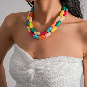 Dettaglio di collana a doppio strato con perle cilindriche in acrilico colorato su modella