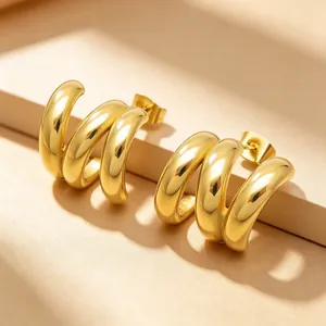 Détail rapproché de boucles d'oreilles en acier inoxydable doré en forme de C