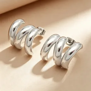 Gros plan sur les boucles d'oreilles minimalistes en forme de C à trois boucles en acier