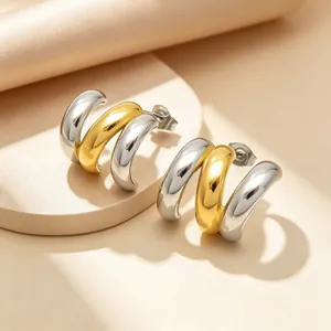 Gros plan de boucles d'oreilles C en acier inoxydable, contraste or et argent
