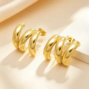 Détail rapproché de boucles d'oreilles en spirale triple en forme de C en acier doré.