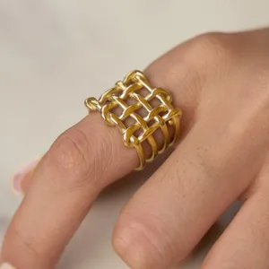 Detailed macro view of a gold-plated stainless steel hollow woven geometric ring on a finger