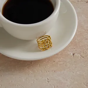 Detailed macro shot of a gold-finished stainless steel hollow woven geometric ring