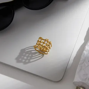 Detailed view of a gold-colored woven lattice ring on a silver laptop surface.