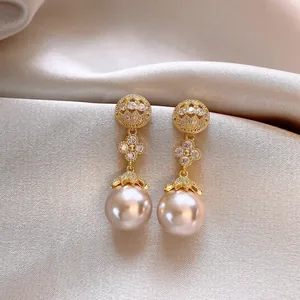 Detail shot of elegant French-style gold hollow-out earrings with sparkling pearl drops.
