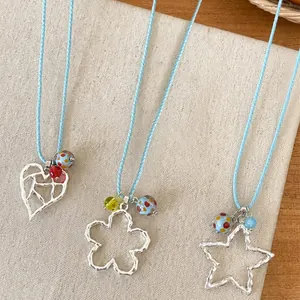 Detailansicht von blauen Kordelhalsketten mit hohlen Herz Blumen Stern Anhängern.