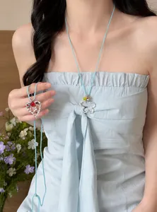 Detailansicht der hellblauen Kette mit ausgehöhltem Blumen- und Herzanhänger am Modell