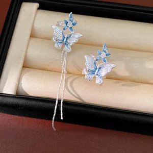 Dettaglio orecchini a farfalla blu asimmetrici con lunghe nappe in argento.