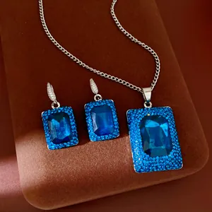 Detail of silver-tone jewelry set featuring blue rectangular gemstones and pavé crystals.