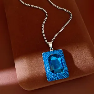 Detailed macro view of a rectangular blue gemstone pendant necklace with brilliant rhinestone border.