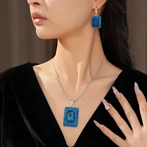 Elegant blue geometric crystal necklace and earring set showcased on a model close-up