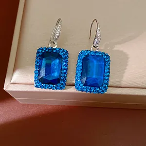 Macro detail of elegant rectangular blue crystal earrings with rhinestone accents.