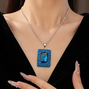 Close-up of a luxurious blue rectangular crystal pendant on a silver chain.