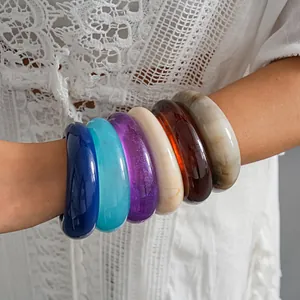 Close-up of colorful chunky resin bangles set on arm with retro marble textures and glitter