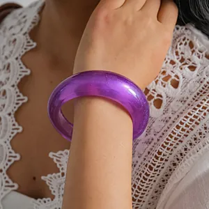 Detailed close-up of a purple translucent resin bangle on model's wrist with white lace