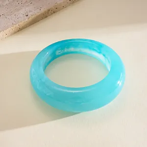 Close-up of minimalist light blue resin bangle with elegant white marbled texture.