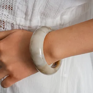 Detail view of retro resin bangle with marble swirl pattern on model's wrist.