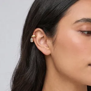 Primer plano de pendiente de clip de acero dorado con cristal rectangular en modelo
