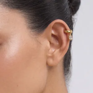 Detalle macro de elegante ear cuff de acero dorado de 18k con cristal en forma de gota