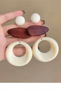 Hand-held view of retro French earrings featuring wooden and cream resin elements