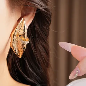 Makroansicht von goldenen lippenförmigen Ohrringen mit Strass-Detail am Ohr.