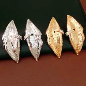 Detailansicht von lippenförmigen Ohrsteckern mit gehämmerter Metallstruktur und Strass