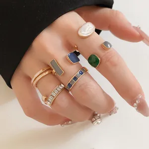 Λεπτομερές κοντινό πλάνο γεωμετρικών χρυσών δαχτυλιδιών με σμάλτο σε χέρι με μανικιούρ