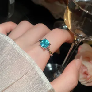 Detailopname van een elegante ring met blauwe vierkant geslepen edelsteen aan de vinger