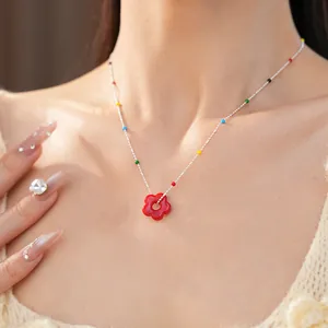 Gros plan détaillé d'un collier avec un pendentif fleur en verre coloré au cou.