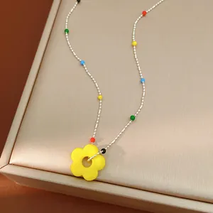 Détail d'un collier fleur en verre coloré avec des perles vibrantes sur chaîne argentée