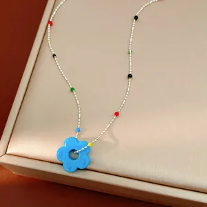Vue détaillée d'un collier coloré style dopamine avec pendentif fleur en verre bleu