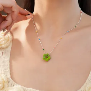Vue détaillée d'un collier fleur en verre vert avec perles colorées sur un mannequin