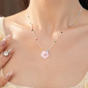 Gros plan exquis d'un collier de fleurs en verre dopamine sur un modèle féminin.