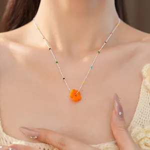 Gros plan d'un collier avec une fleur en verre orange sur une chaîne argentée