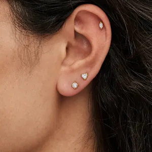 Close-up of gold stainless steel stud earring set on ear with heart and marquise shapes