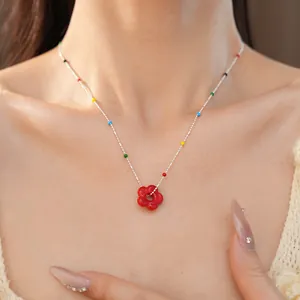 Gros plan d'un collier fleur en verre rouge sur modèle avec de jolies perles colorées