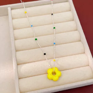 Gros plan d'un pendentif fleur en verre jaune sur un collier de perles colorées
