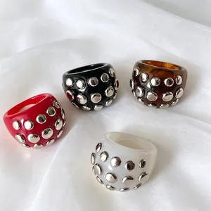 Close-up view of punk style resin rings with silver metal rivets in four stylish colors.