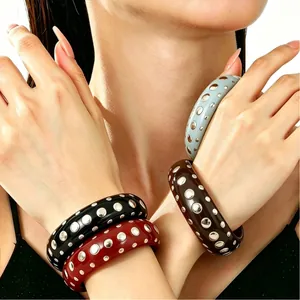 High-quality close-up detail of punk style resin bangles with silver rivets on a model