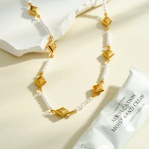Detalle de collar de acero inoxidable dorado con rombos y perlas blancas.