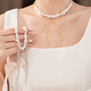 Elegante collana di perline bianche con stella marina dorata e nappe di catena in metallo