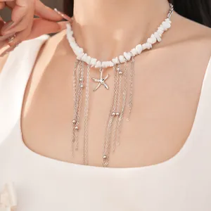 Primo piano di una collana di pietre bianche con pendente a stella marina e nappe a catena.