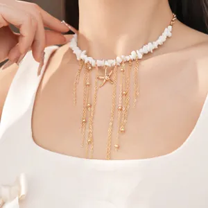 Dettaglio della collana in pietre bianche con nappe dorate e ciondolo a stella marina