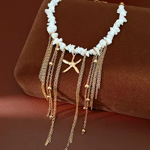 Dettaglio collana con perline di pietra bianca, ciondolo a stella marina e nappe oro.