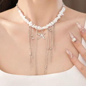 Primo piano di una collana di pietre bianche con ciondolo a stella marina e nappe.