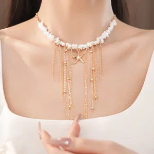Dettaglio della collana con stella marina, perle di pietra bianca e nappe dorate