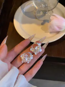 Dettaglio di orecchini a cerchio a cesto di fiori in argento con perle e pietre di zircone.