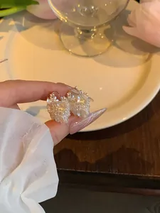 Dettaglio ravvicinato di orecchini a cerchio romantici con perle e zirconi