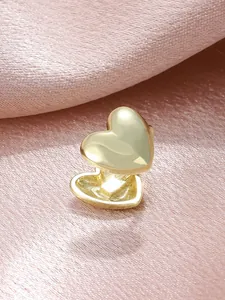 Close-up detail of a minimalist gold heart-shaped non-pierced clip-on earring on pink silk