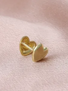 Close-up detail of minimalist golden heart-shaped ear clips on elegant pink silk background